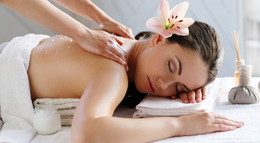 Therapist performing unisex body massage at spa