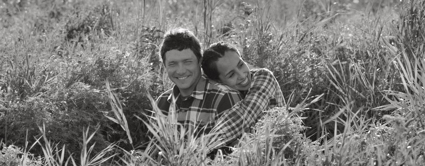 a man and a woman are sitting in the grass