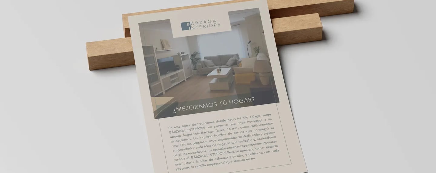 Flyer promocional de Bárzaga Interiors puesto sobre dos listones pequeños de madera
