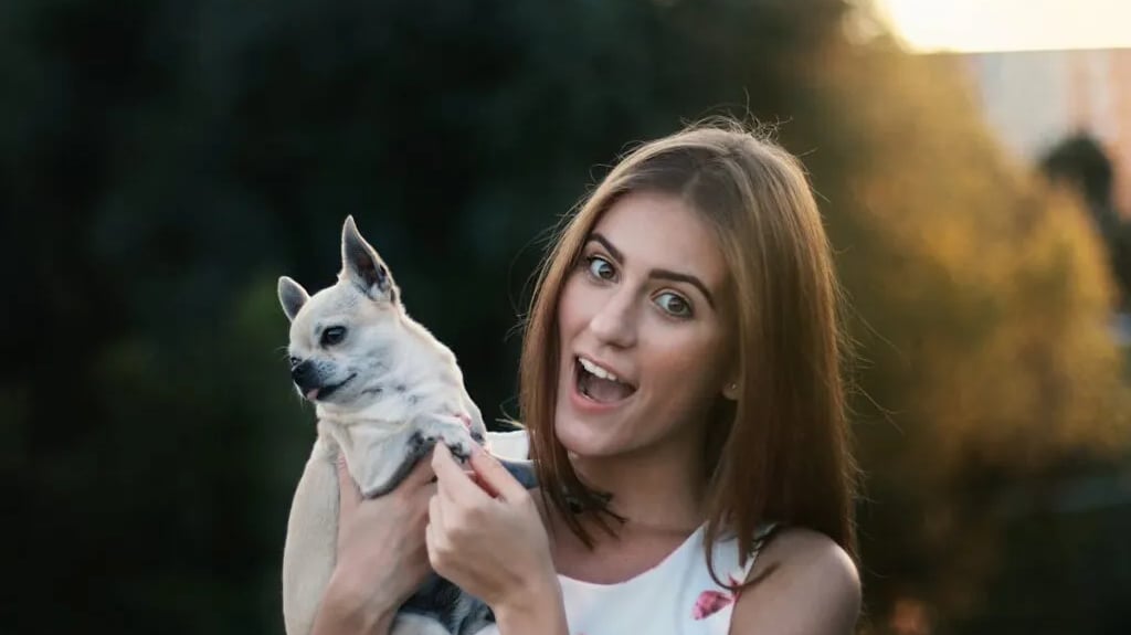 A woman holding a white puppy