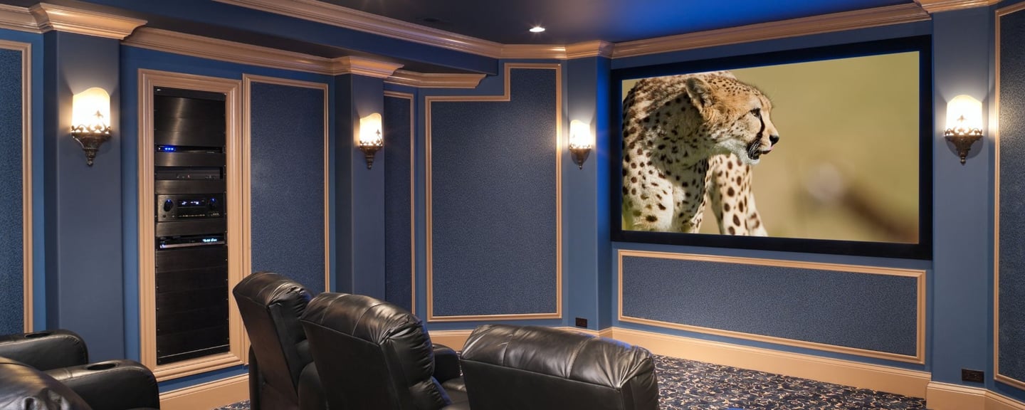 A high-end home cinema featuring a large projection screen, elegant black leather seating.