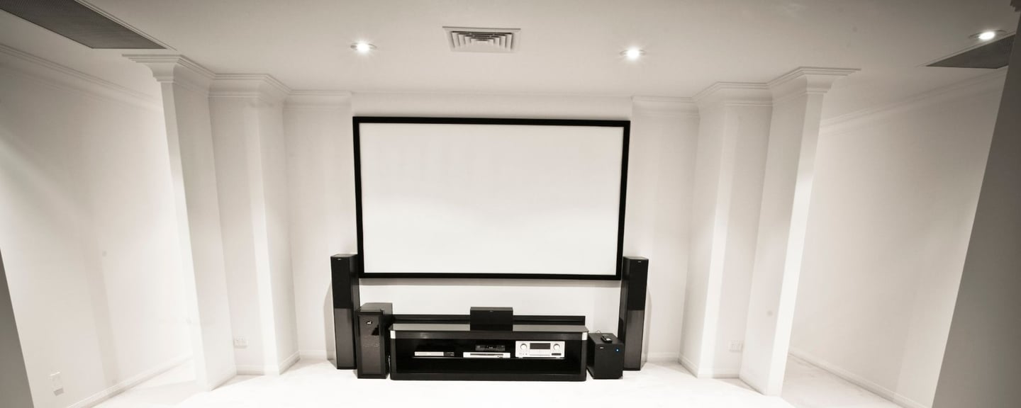 A modern entertainment setup with a wall-mounted projection screen, speaker system.