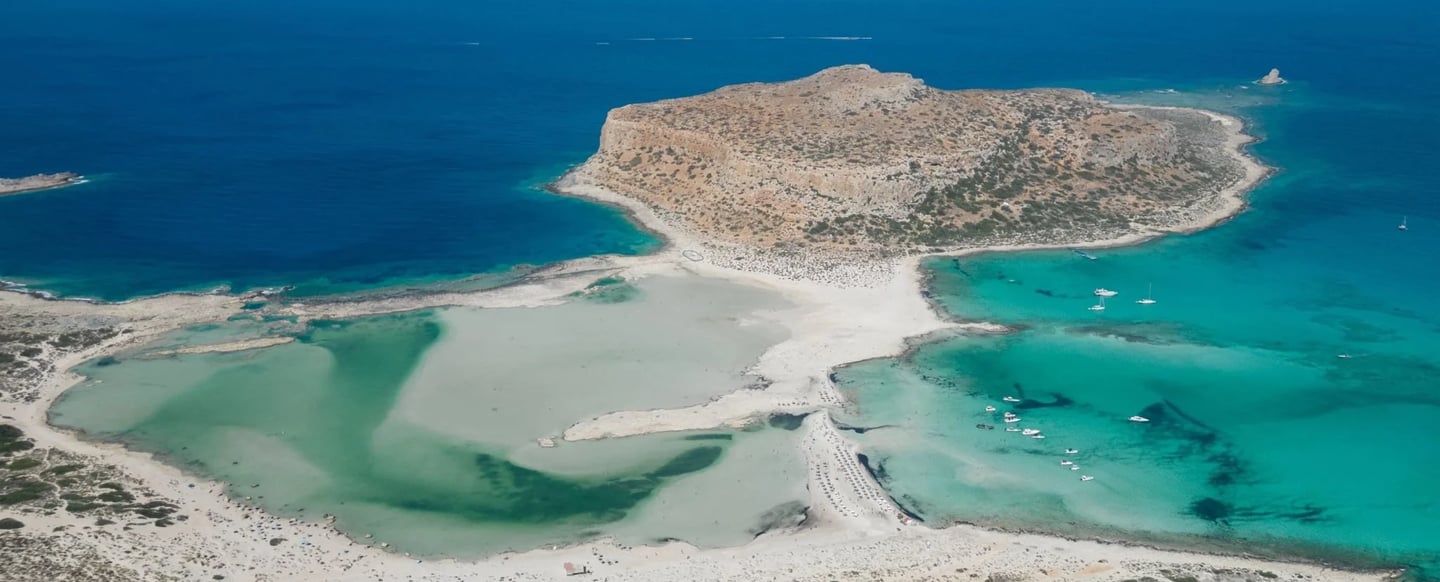 Aerial view of Balos Lagoon in Crete featuring turquoise waters and white sand beach.