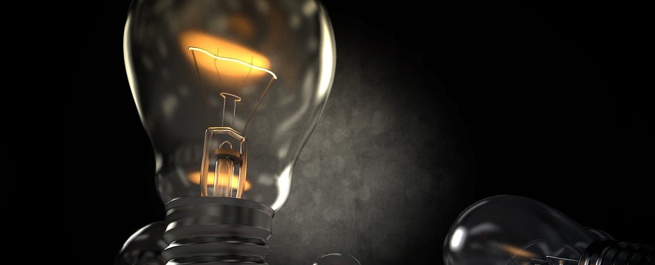 Zbliżenie na żarówkę. Na ciemnym tle dokładnie widać rozgrzany żarnik