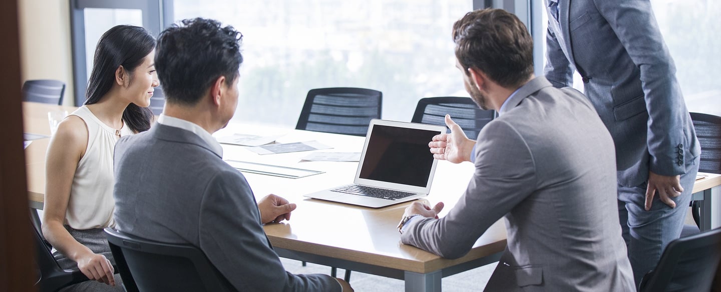 a man and woman sitting at a table with laptops