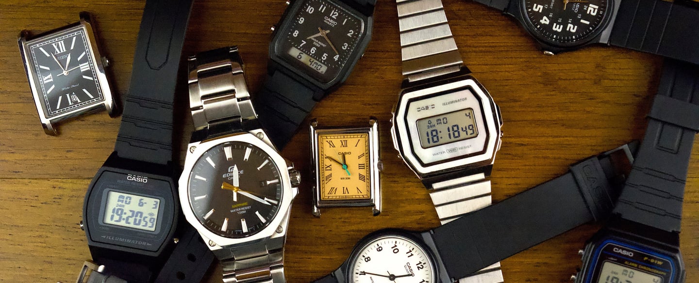a bunch of watches on a table with a clock