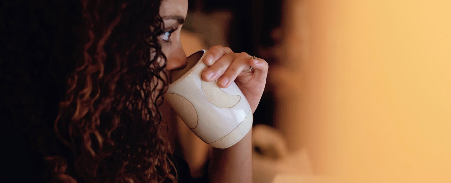 A young girl drinking tea from a porcelin white mug