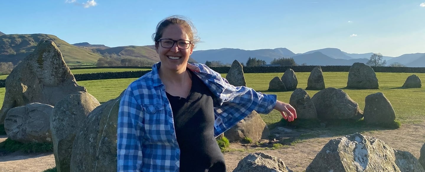 a woman standing in front of a large rock formation