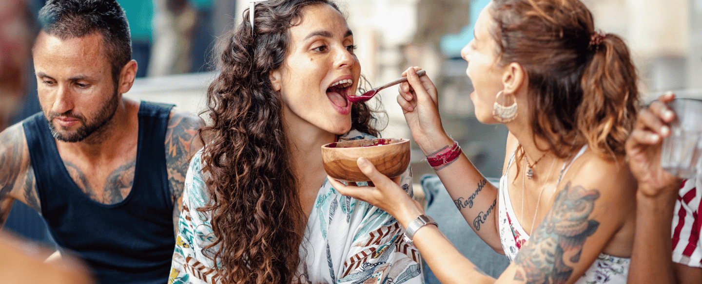 a woman eating a bowl of food while a man is eating