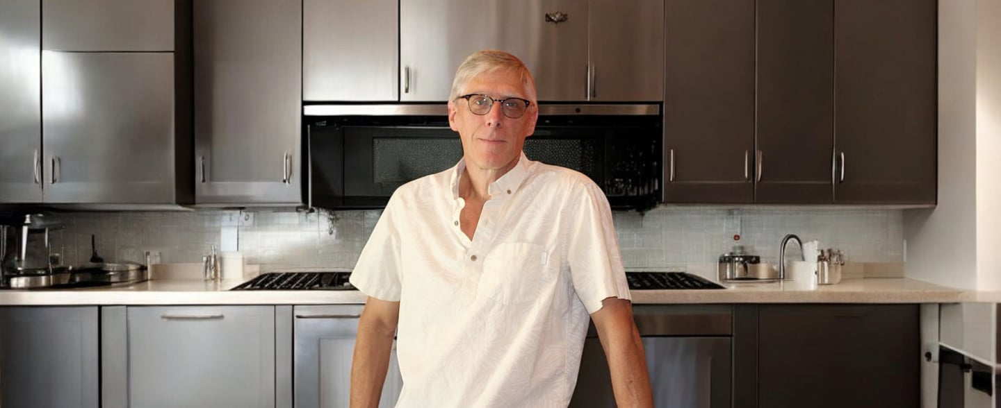 a man standing in a kitchen with a table and chairs