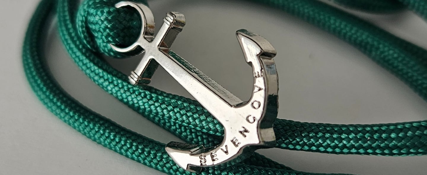a silver anchor anchor on a green rope