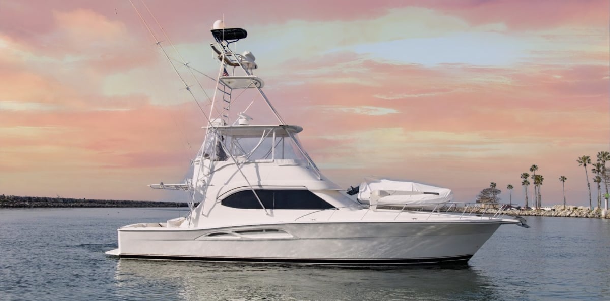 a boat in the water with a pink sky and palm trees