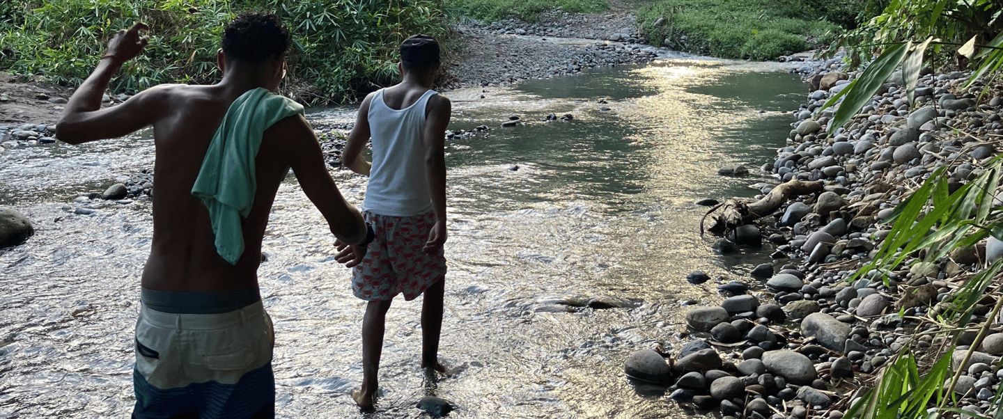 Two men cross the river near camping babsita in costa rica