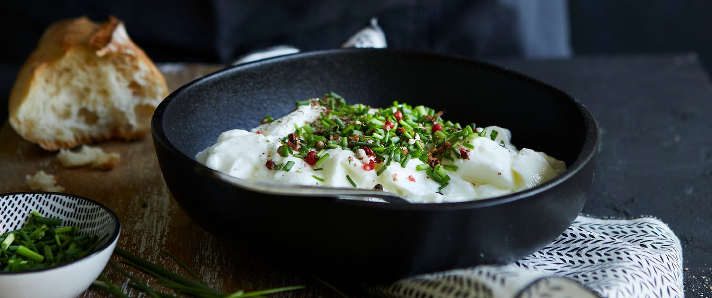 bol noir contenant de la faisselle avec de la ciboulette en morceau et baies rose dans un ambiance f