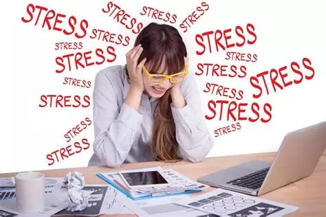 Femme stressée penchée en avant avec lunettes jaunes, se tient la tête mains sur les oreilles