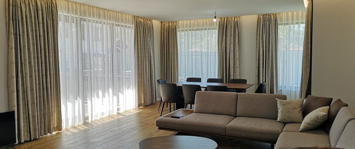 Ein helles Esszimmer mit skandinavischen Möbeln und Fensterfront mit schönen Vorhängen