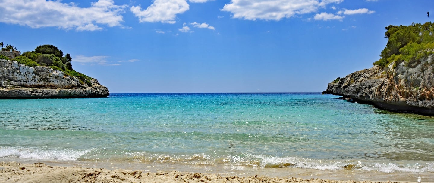 Cala Anguila beach in Mallorca with a blue sky and some clouds