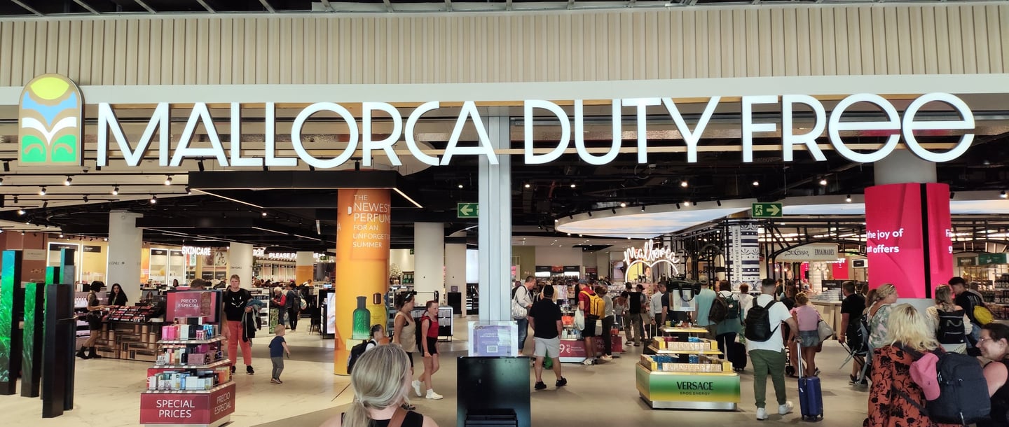a mallorca airport duty free storefront with people walking through the mall