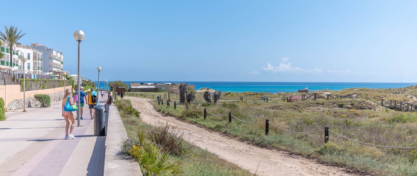 a group of people walking down a path at Cala mesquida, Mallorca