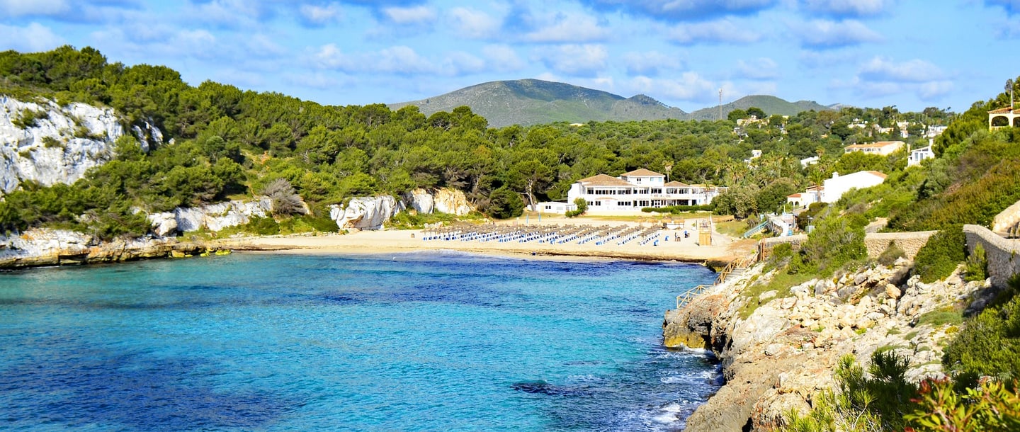 a view of a cala romantica beach in mallorca with a boat in the water