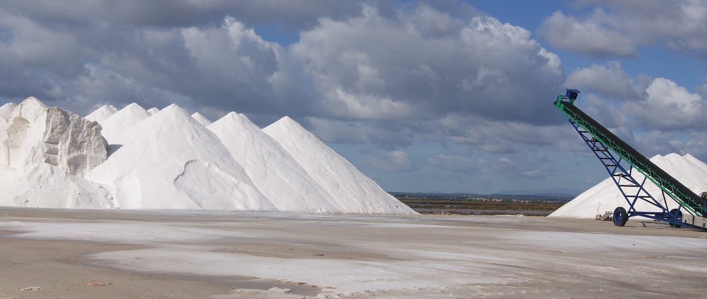 Large white salt piles at a salt production facility in Ses Salines Mallorca under a cloudy sky