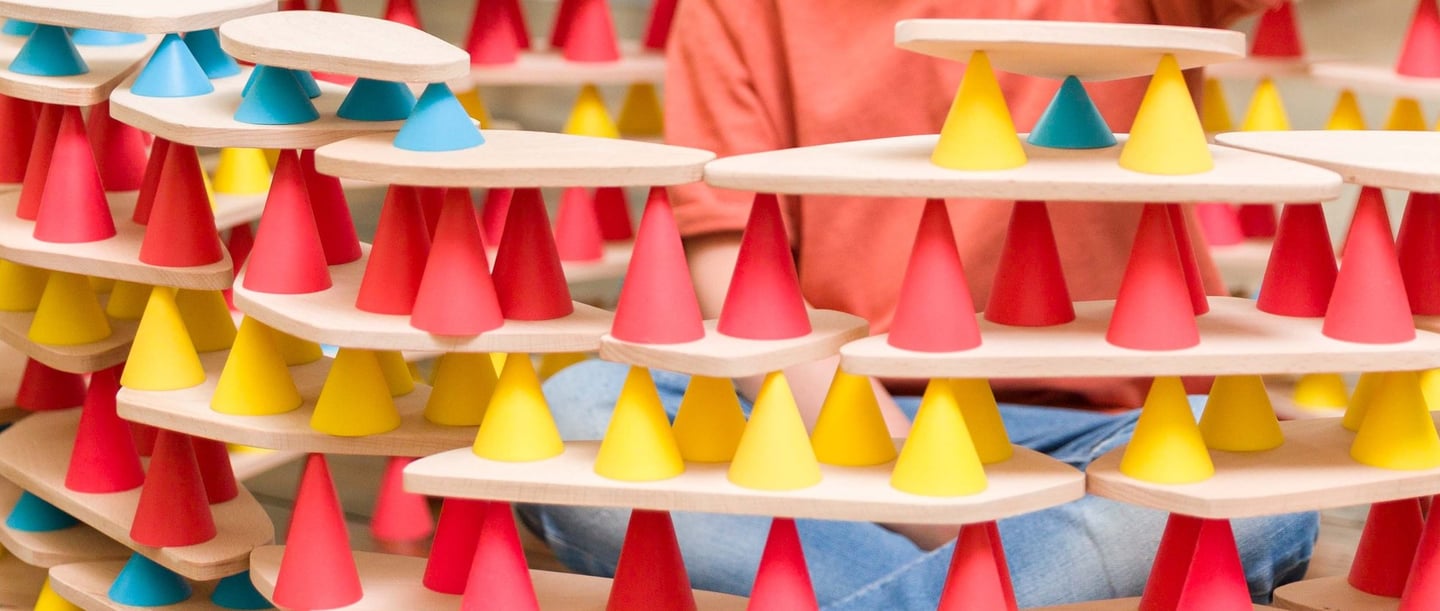 The child plays with silicone cones and wooden tables and creates the desired structure