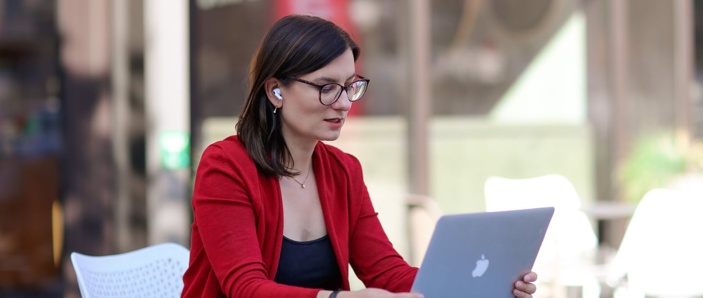 a woman sitting at a table with a laptop computer, talking