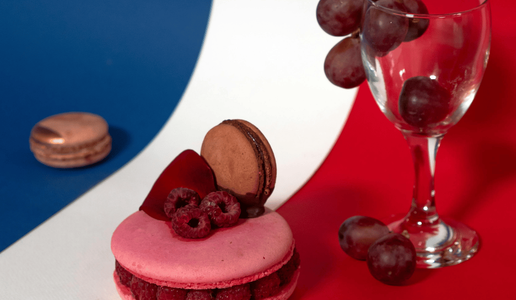 a macarons dessert with a glass of wine and grapes on a French flag