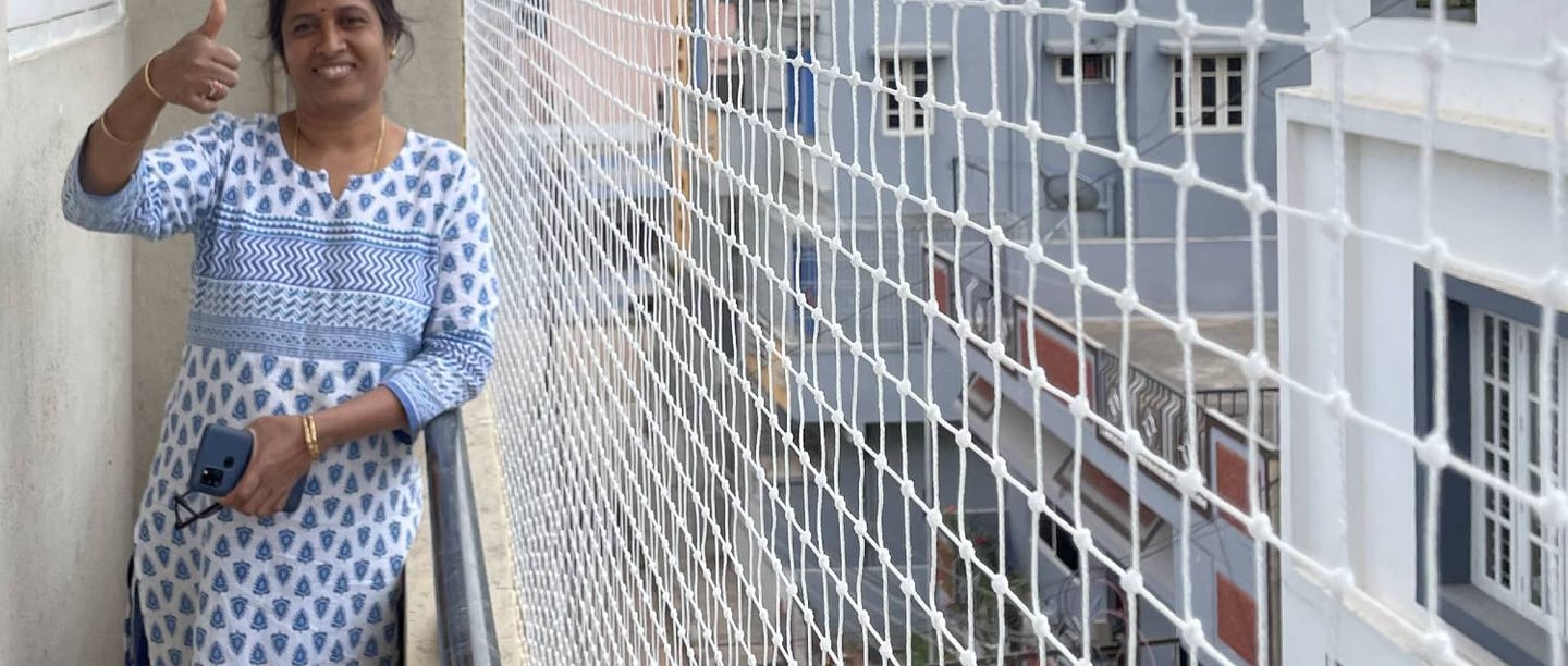 Technician carefully installing a pigeon net on a residential balcony in Chennai.