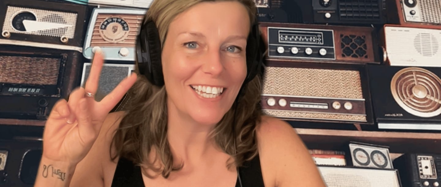 emma scott with headphones displaying the peace sign radios in the back ground 