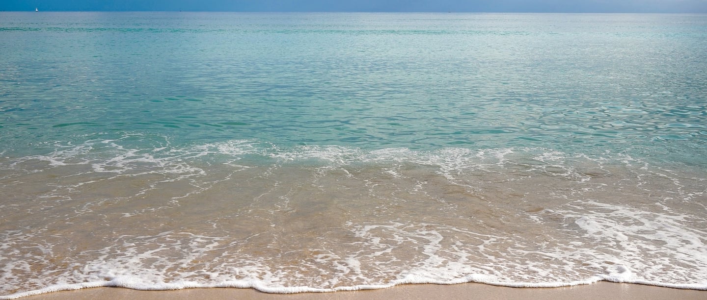 beach with crystal clear water washing on the sand in Playa de Muro Mallorca