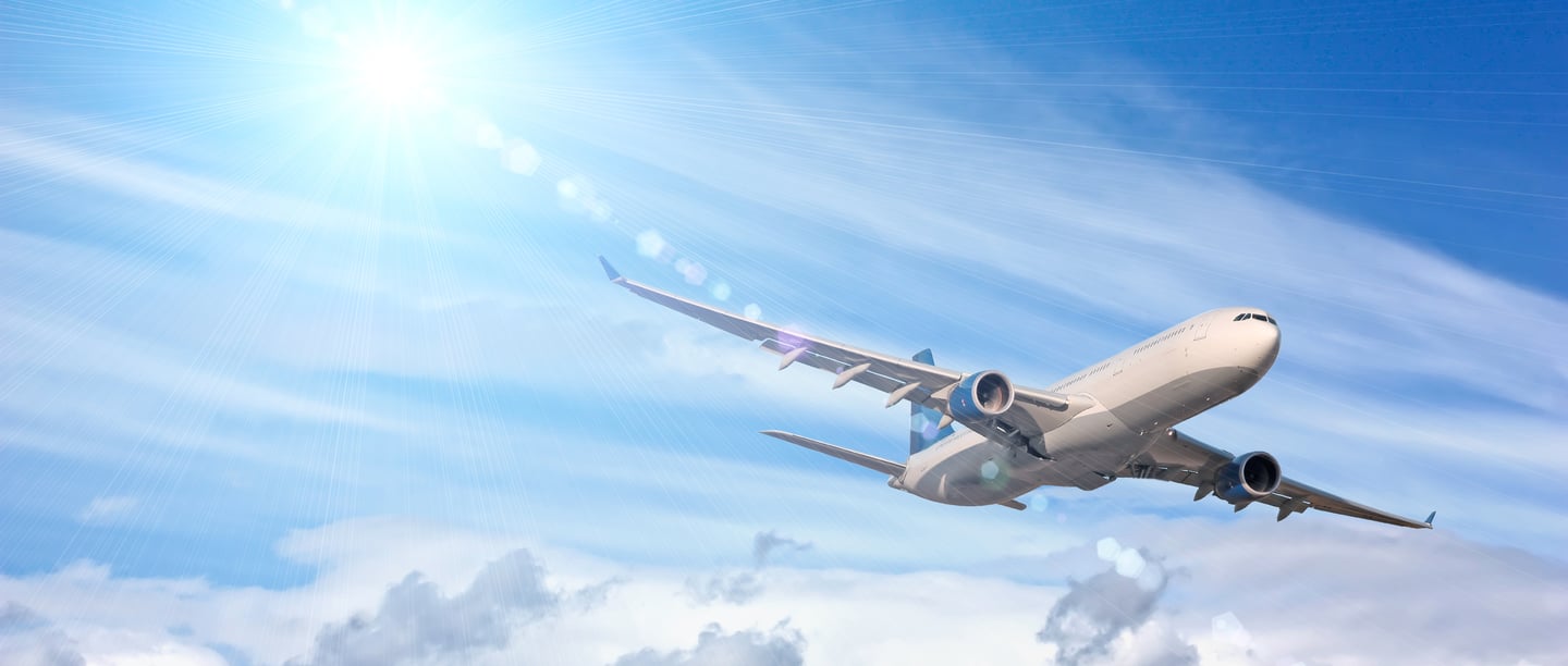 a plane flying in the sky with a bright sun shining on the clouds