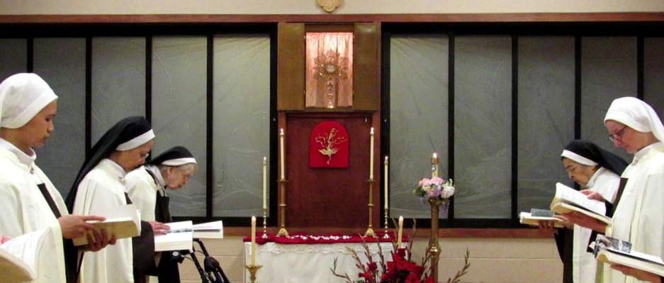 Nuns praying in the choir with the Blessed Sacrament exposed.