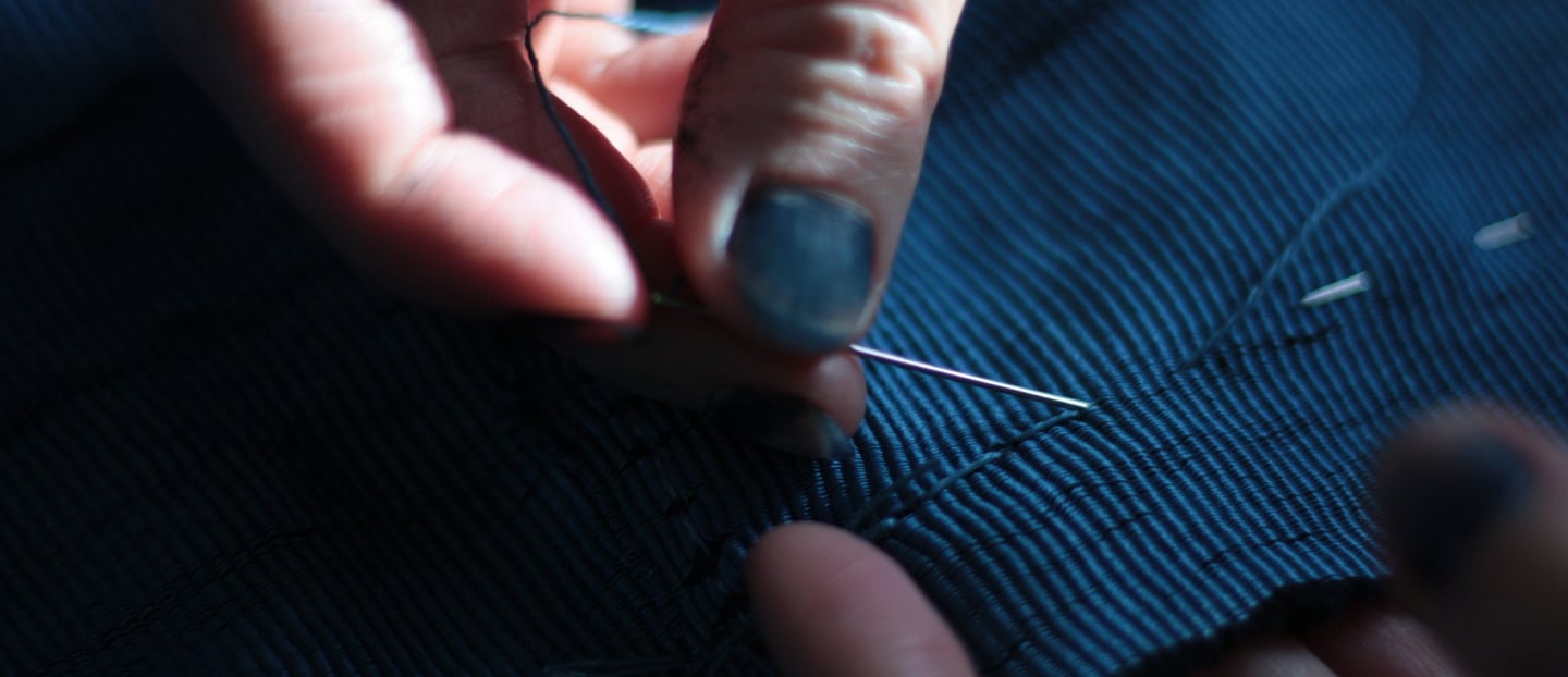 artist sewing her own textiles dyed in her indigo vat