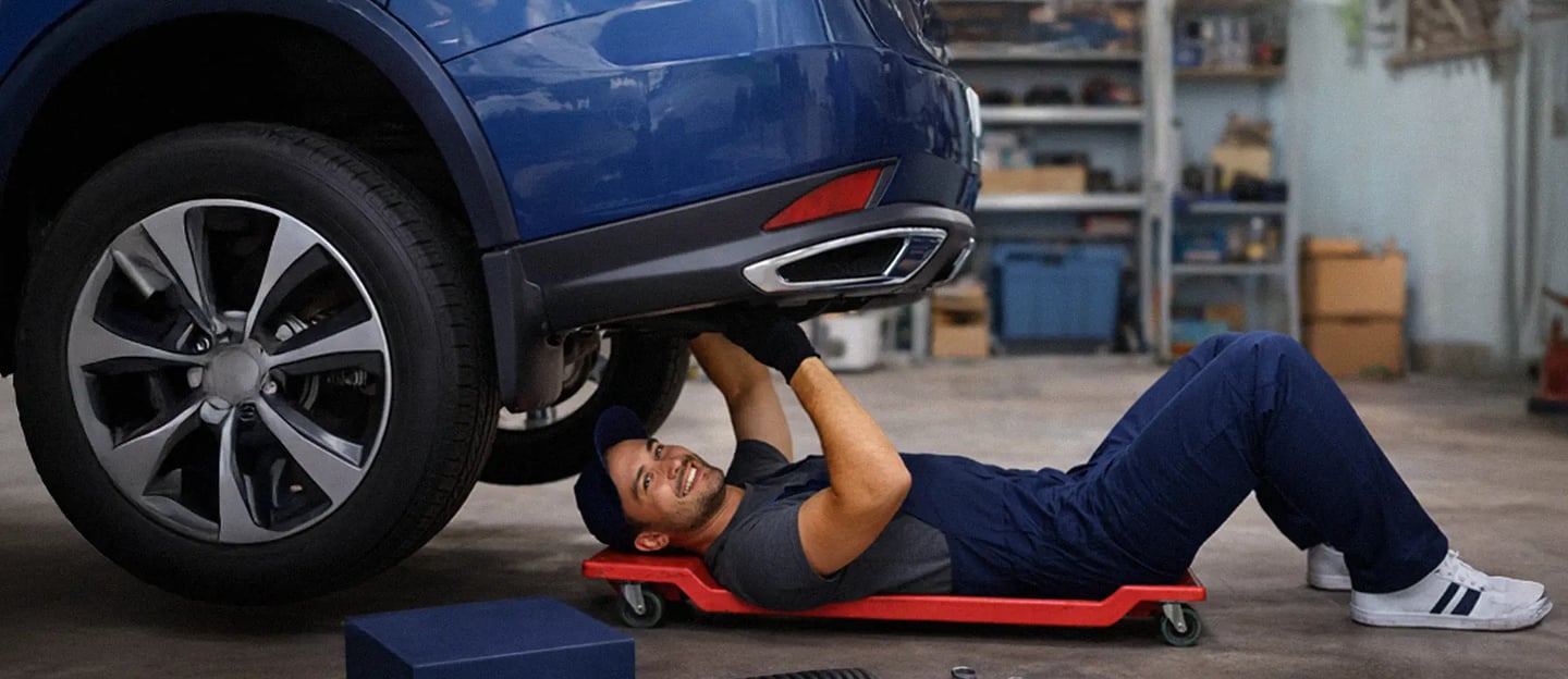 Meccanico sotto l’auto con scatola Hulemex, esempio di packaging coordinato e branding consapevole.