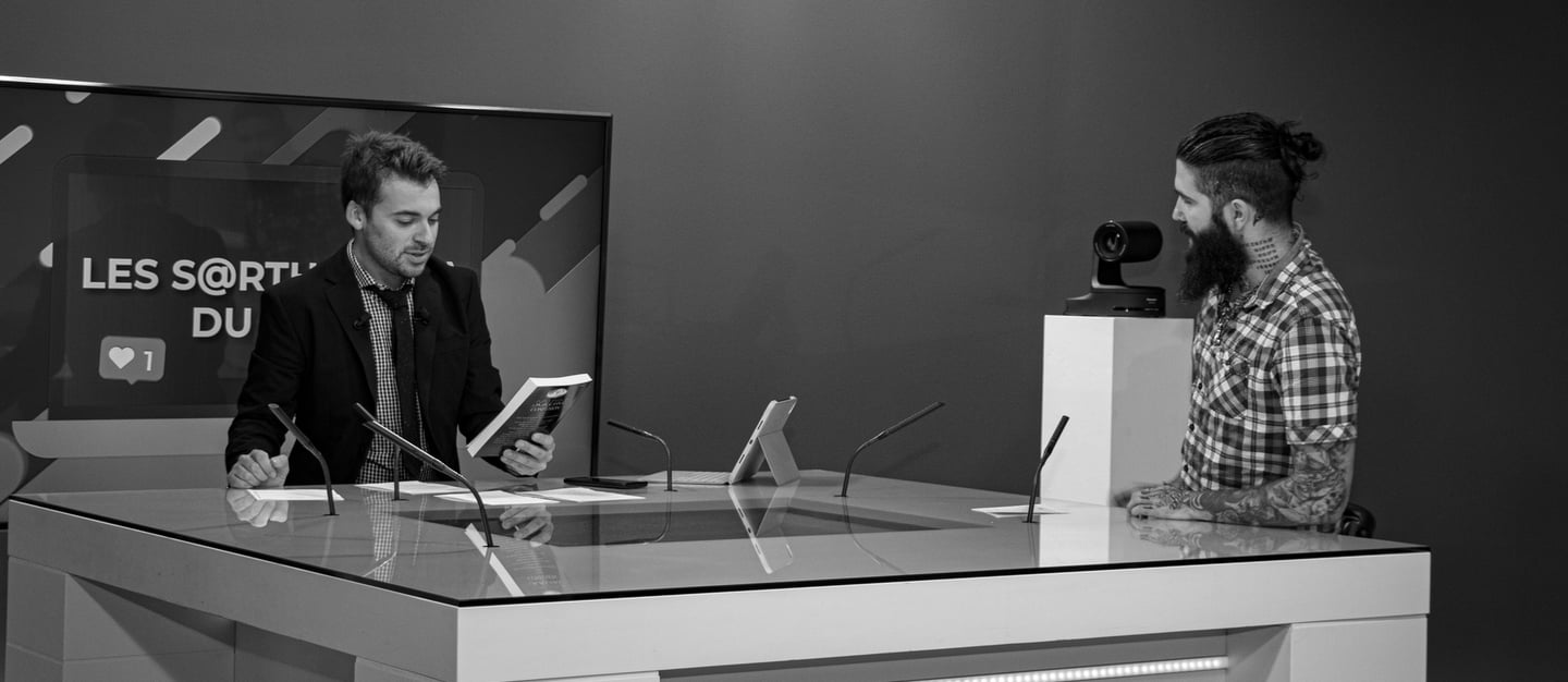 a man in a suit and tie is LMtv Sarthe Aurélien Cailloce itting at a desk with a laptop