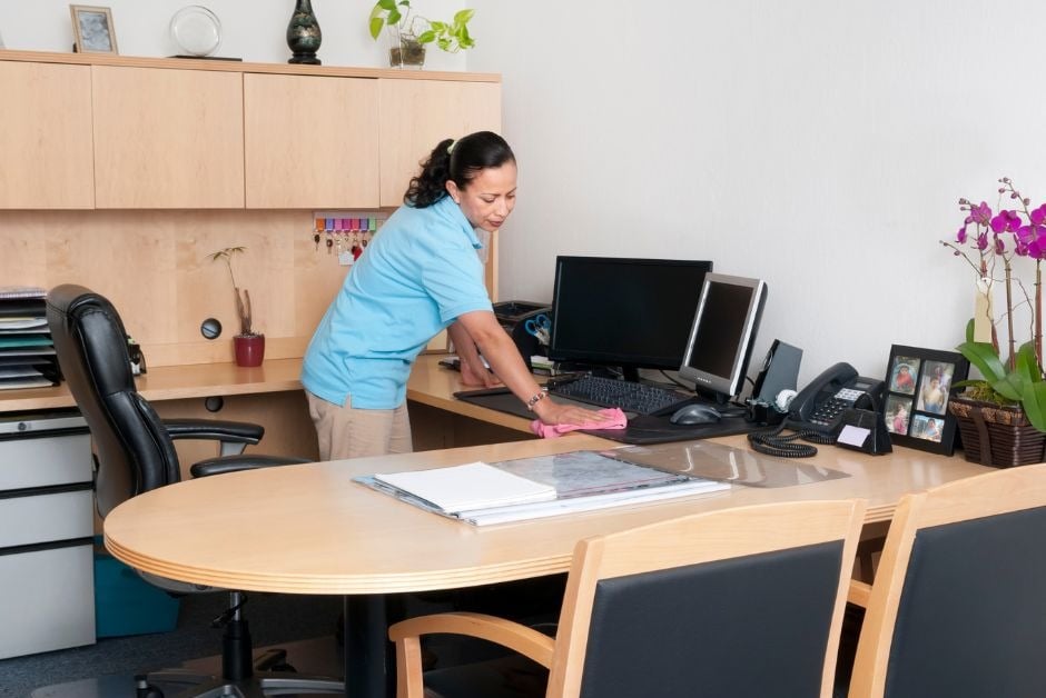 Office cleaner cleaning an office desk