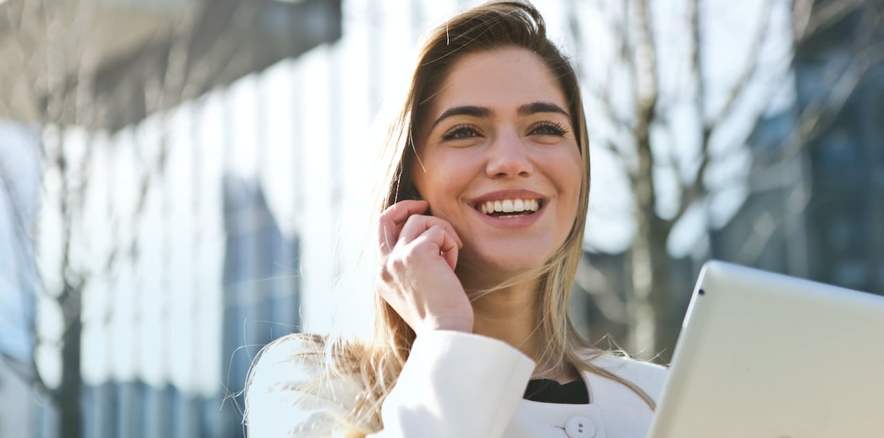 a woman talking on her cell phone and holding a tablet