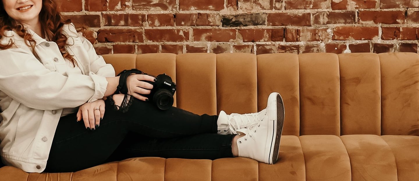 Rachel sits on a couch smiling at the camera