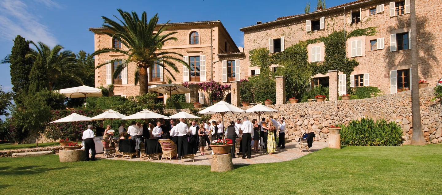 Luxury destination wedding reception at a historic stone villa in Mallorca with white umbrellas.