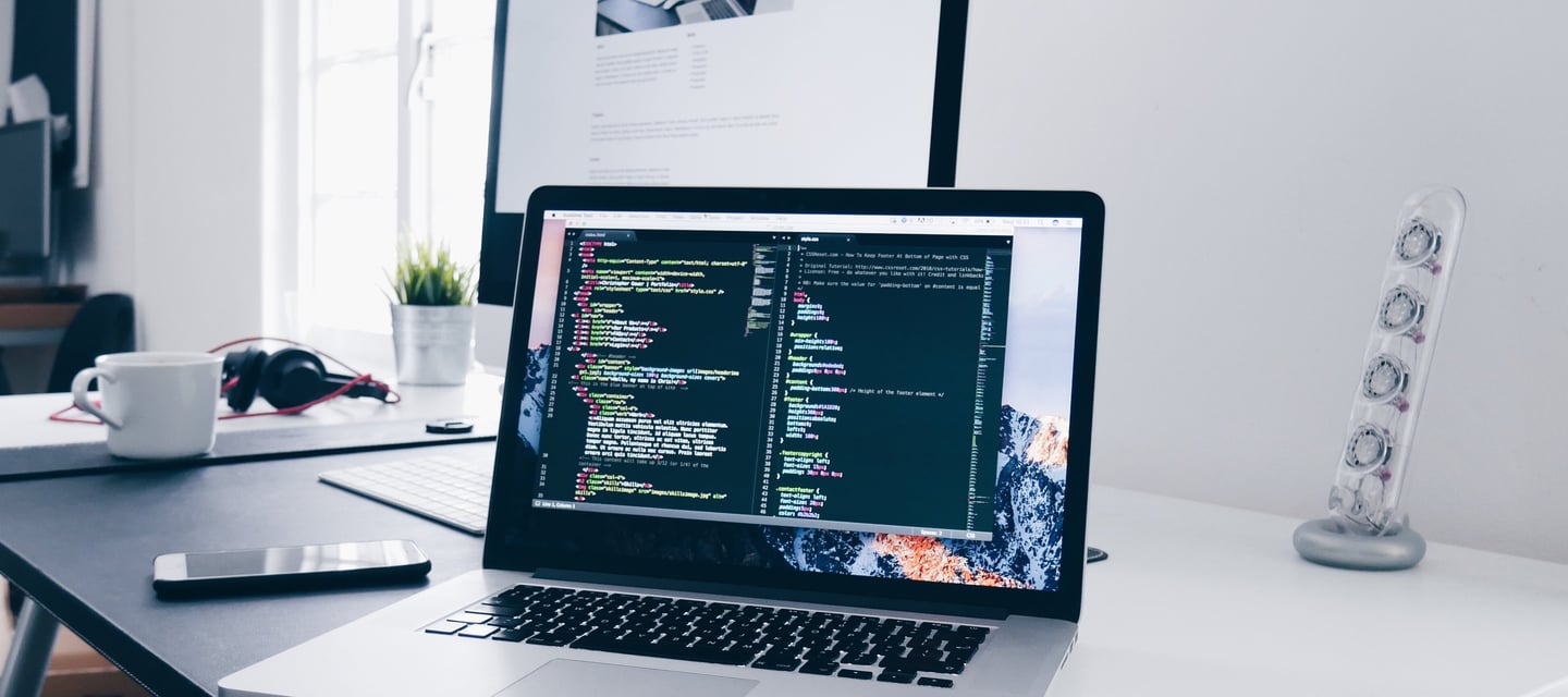 a laptop computer sitting on a desk with a monitor and a keyboard
