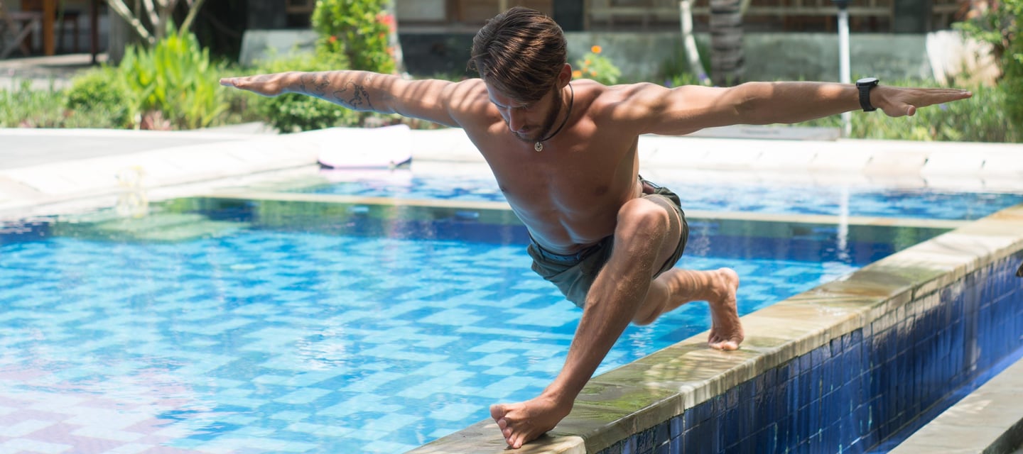 a man is doing a yoga pose on a pool side