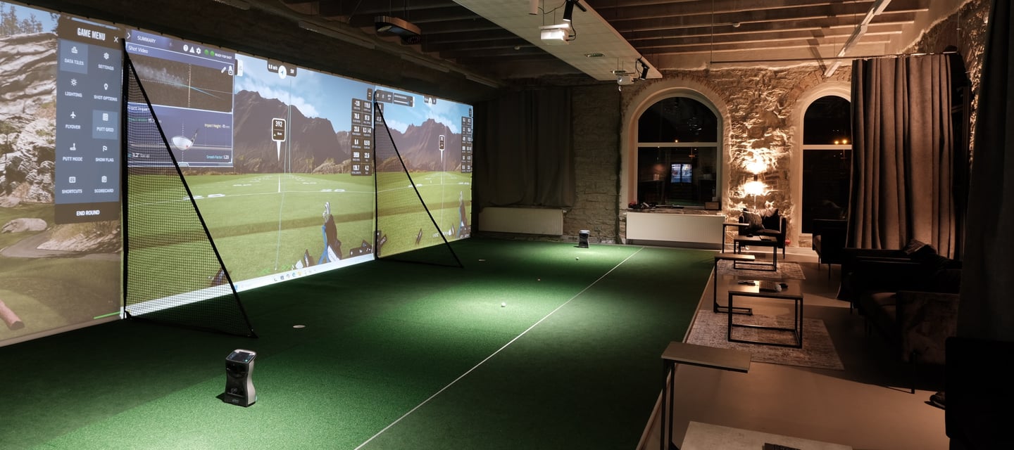 a man is playing golf in a room with a large screen