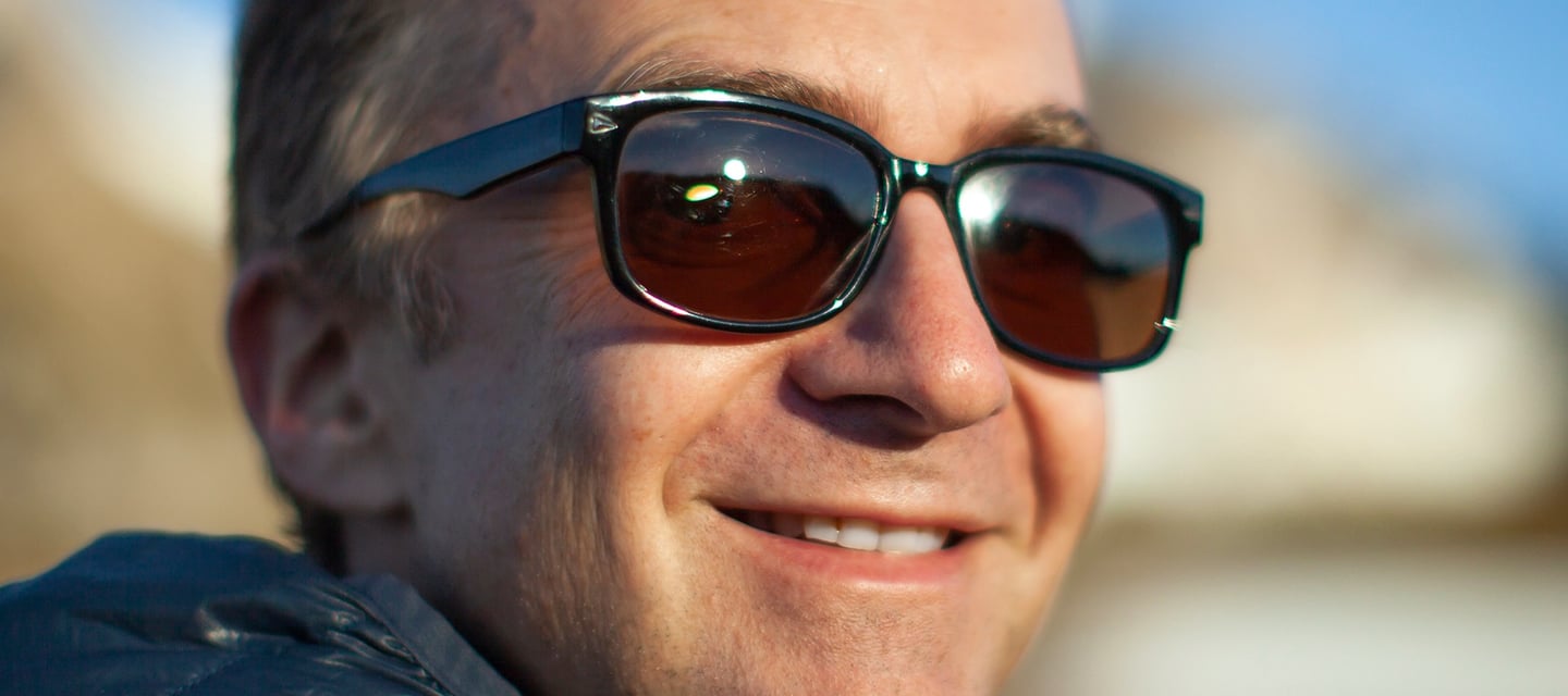 a man in sunglasses and a jacket is smiling