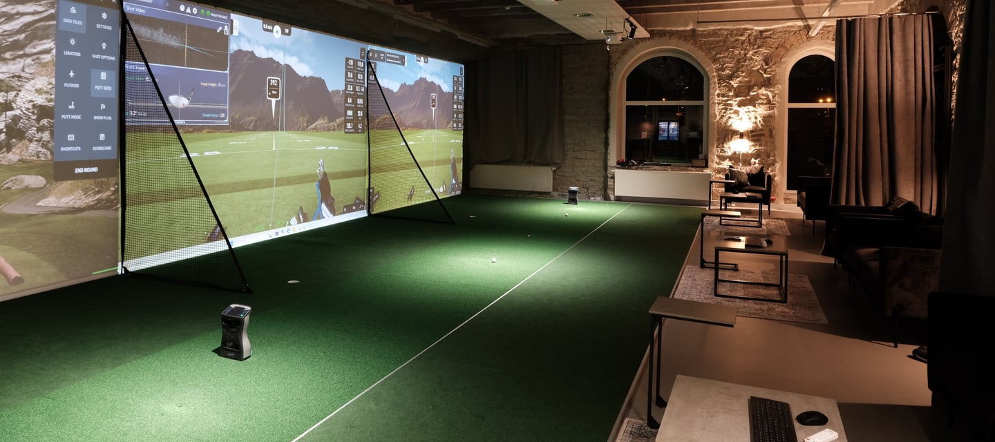 a man is playing golf in a room with a large screen
