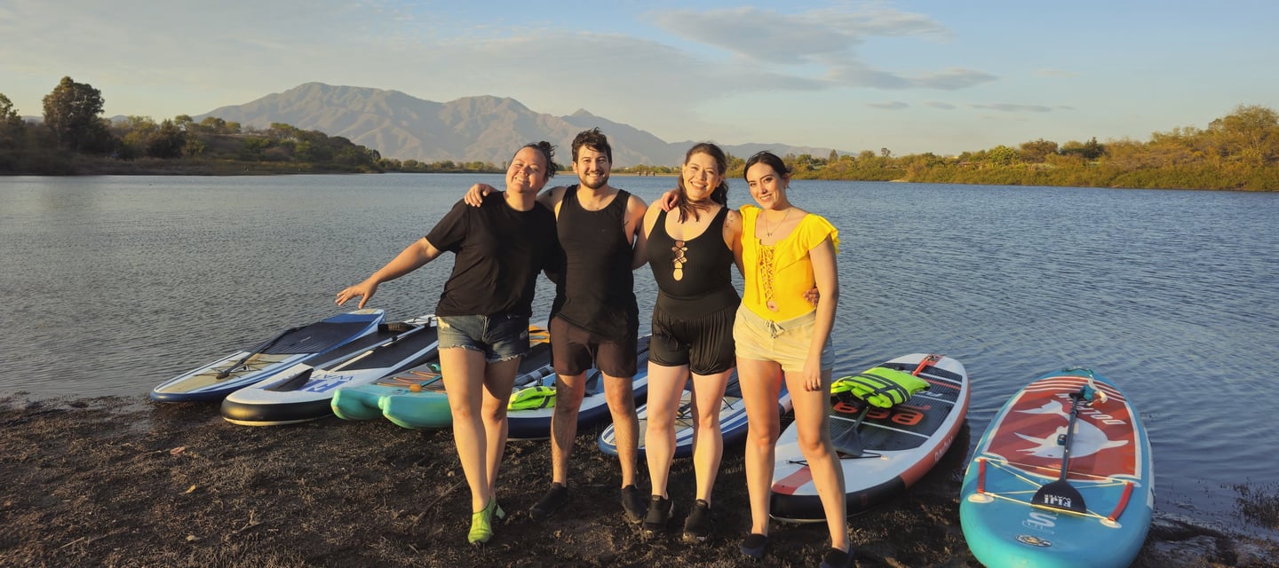 Jovenes disfrutando de un día soleado en la natulareza realizando una experiencia de stand up paddle