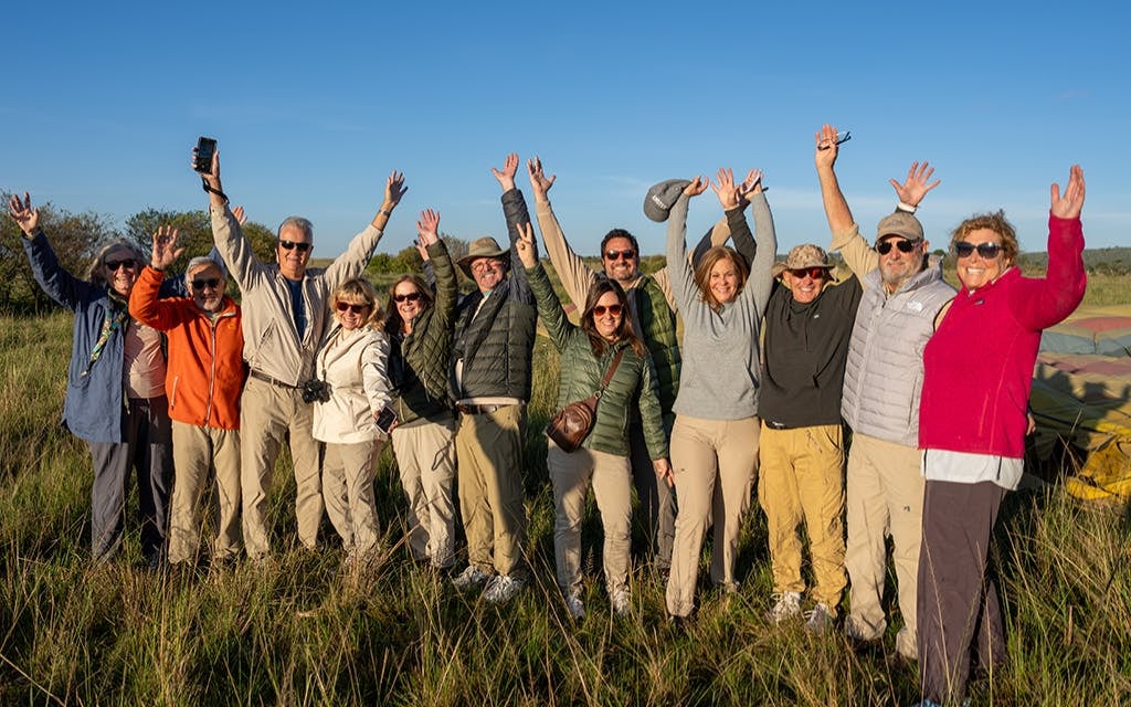 A groups of travelers with their hands in the air, men and womenprovided by Tauck Travel