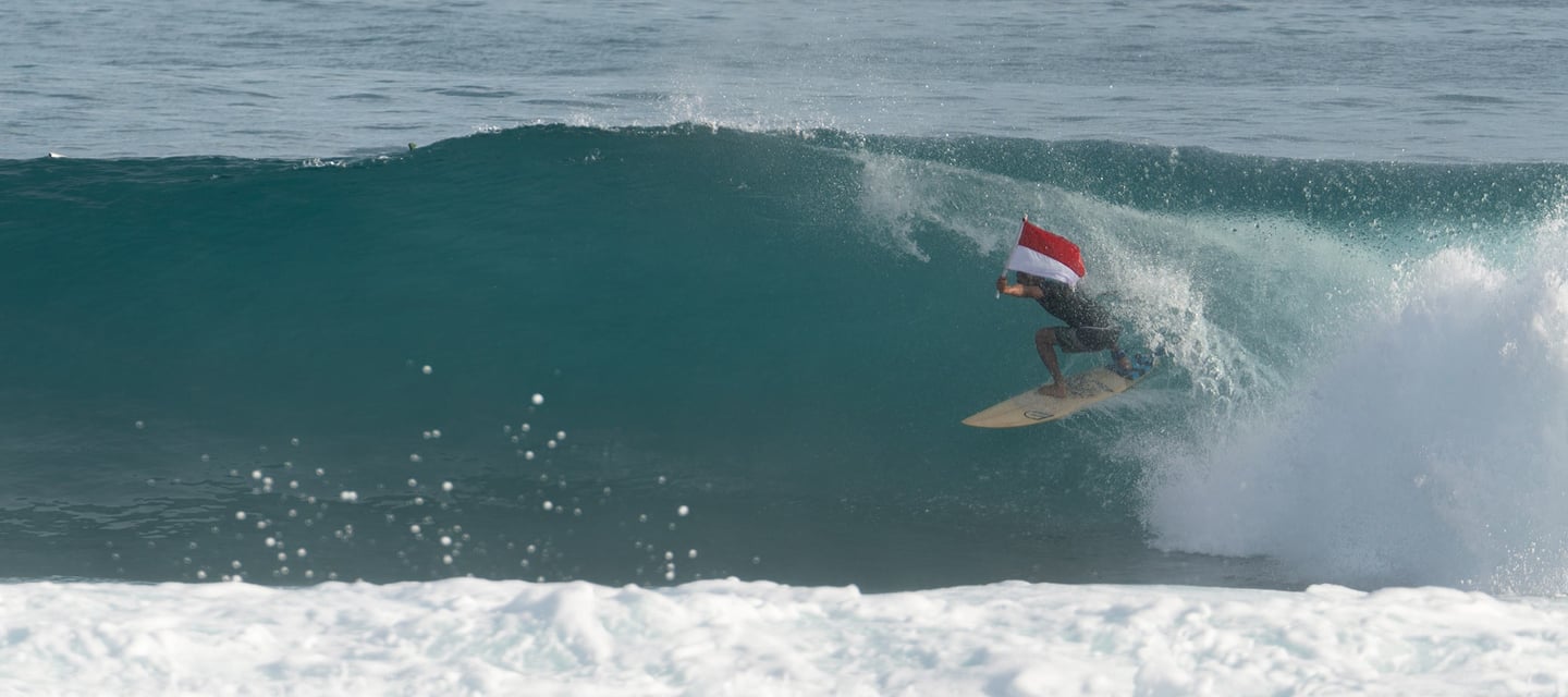 surfing dylans in simeulue holding indonesian flag - stay with the locally owned camps!