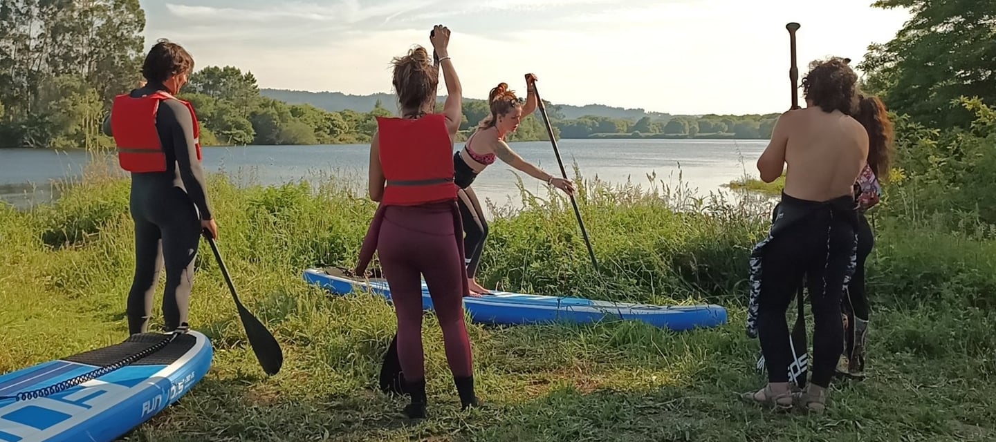 Instructora de paddle surf explicando mientras el grupo de 4 escucha