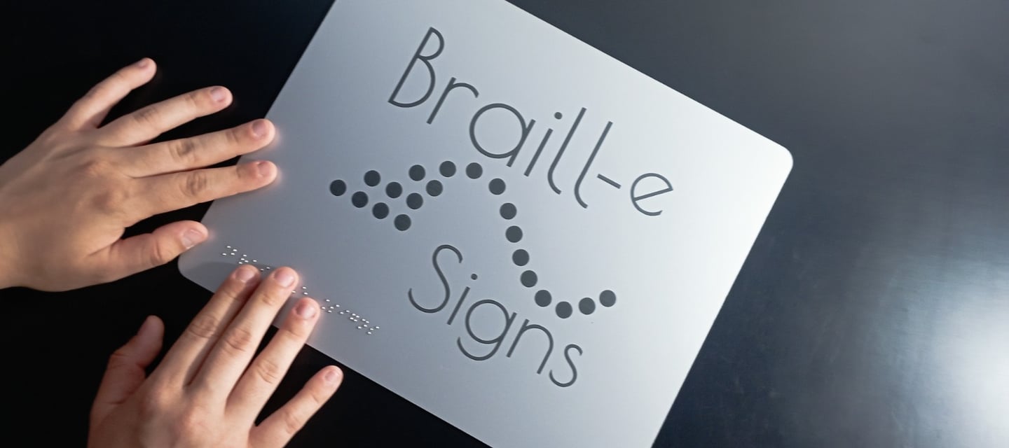 a person holding a sign that says braille signs